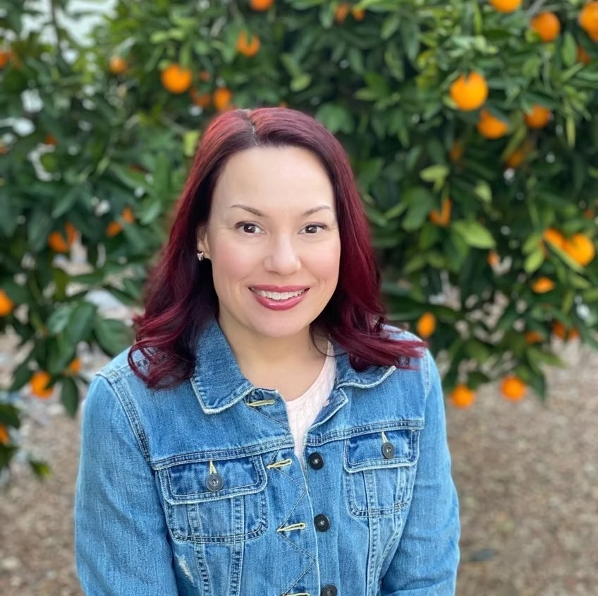 Tabitha Intschert, LCSW, PYT, in front of an orange tree